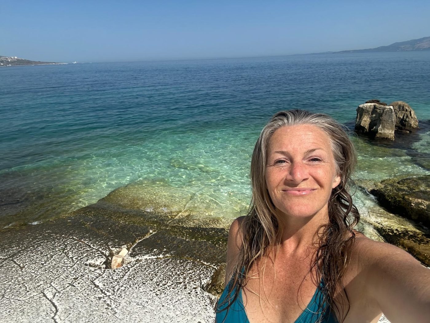 Maya Lila Di Vento smiling beside clear turquoise water on the Ionian coast
