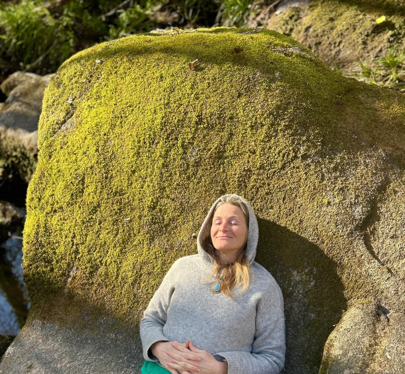 Maya Lila Di Vento resting with closed eyes against a huge moss-covered boulder in France