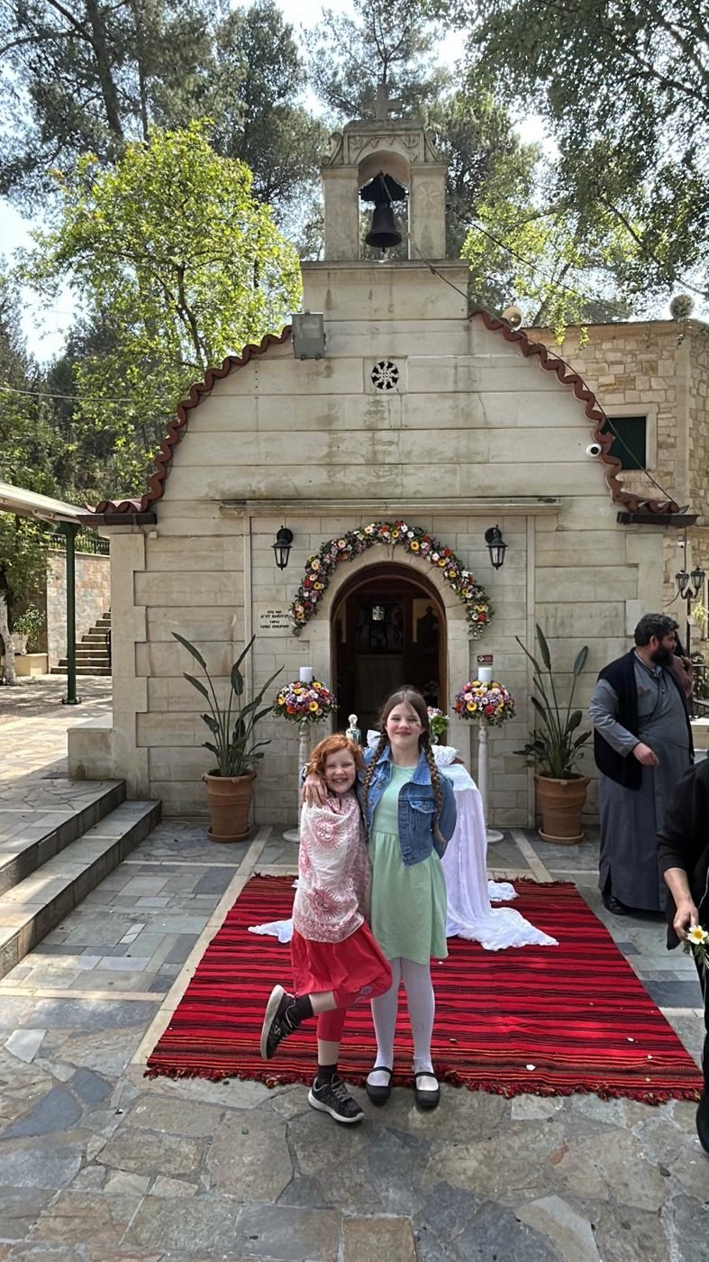 Two girls in front of the flower-decked ancient church of St Phanourios in Crete